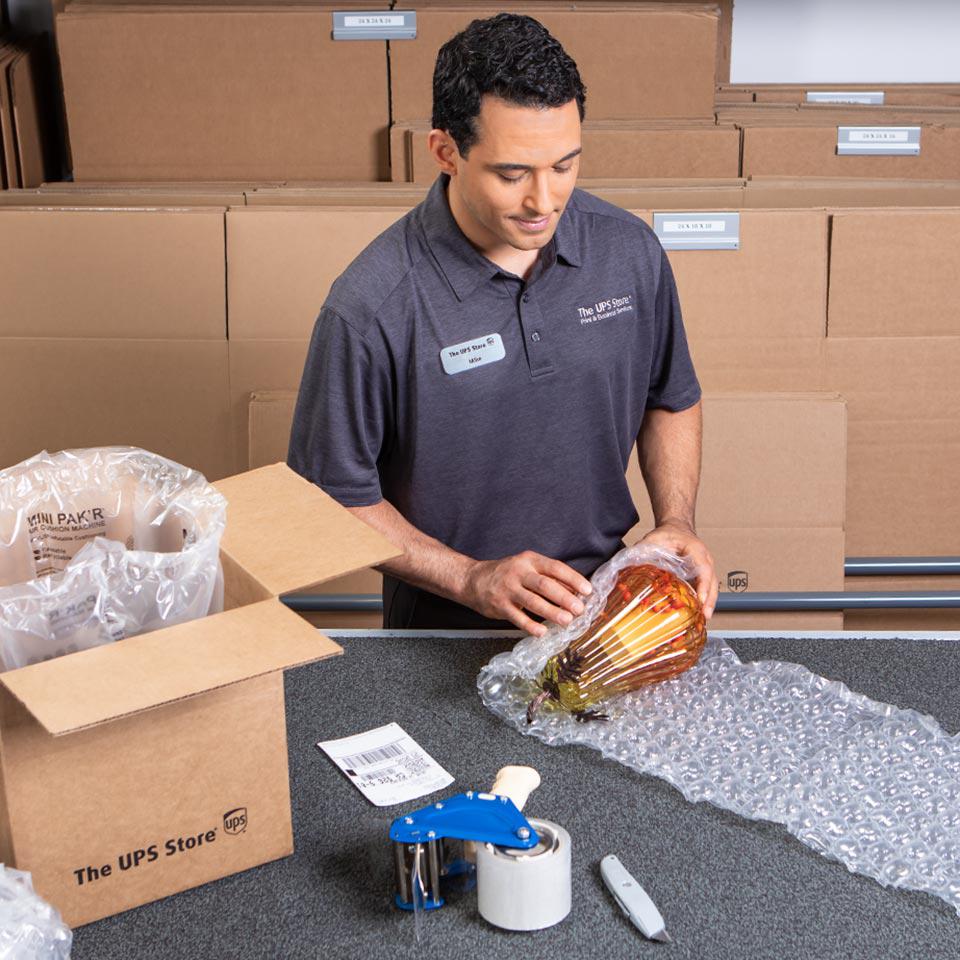 Associate at The UPS Store packing fragile item for shipment