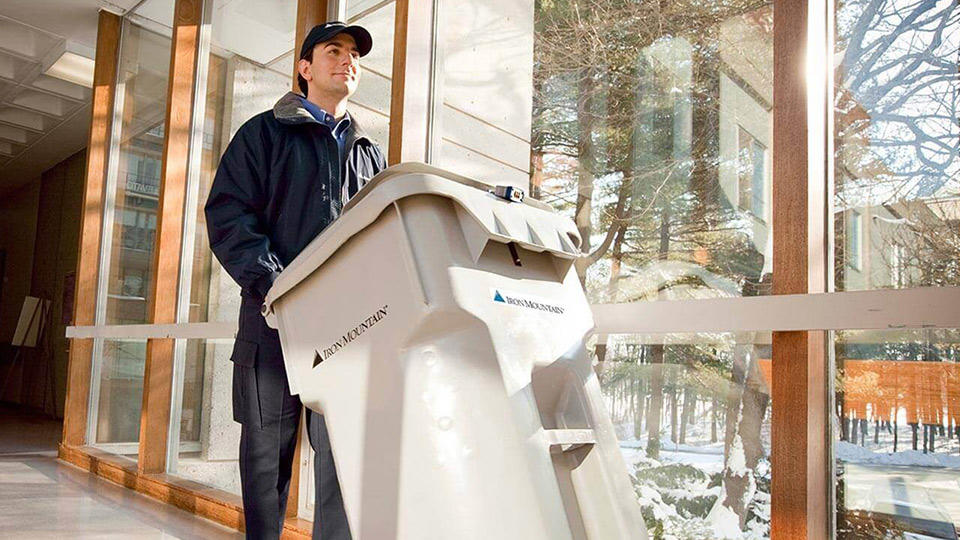 iron mountain employee wheeling out an iron mountain shredding bin for secure disposal