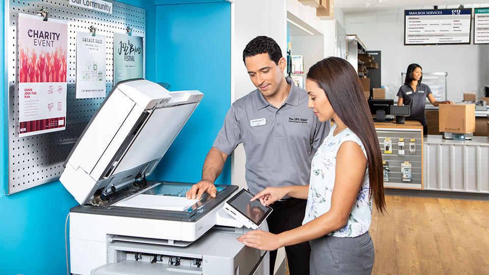 The UPS Store associate helping a customer scan some documents