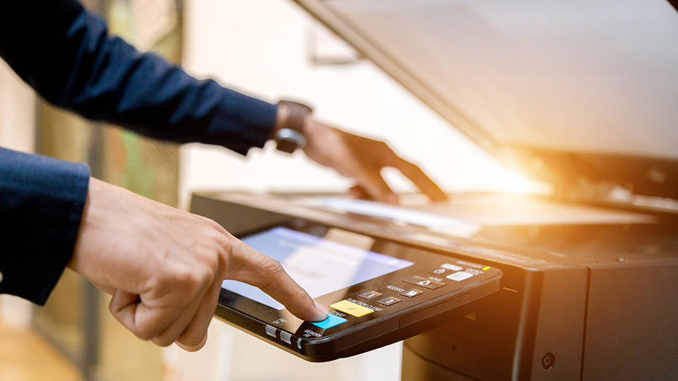 A hand pressing the button on a scanning machine at The UPS Store