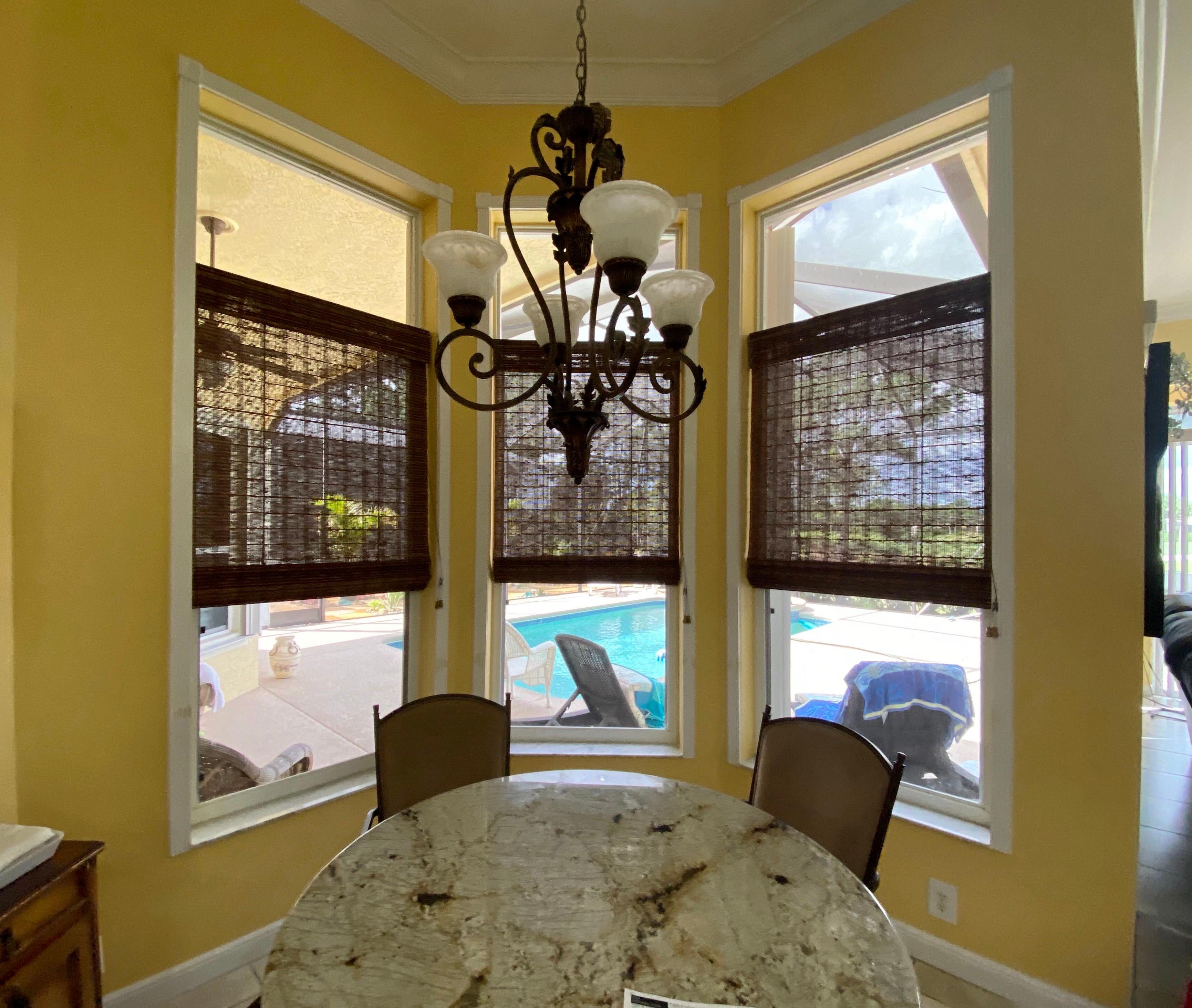 Woven wood fabric shades add texture and interest to this dining nook, along with a tropical feel.