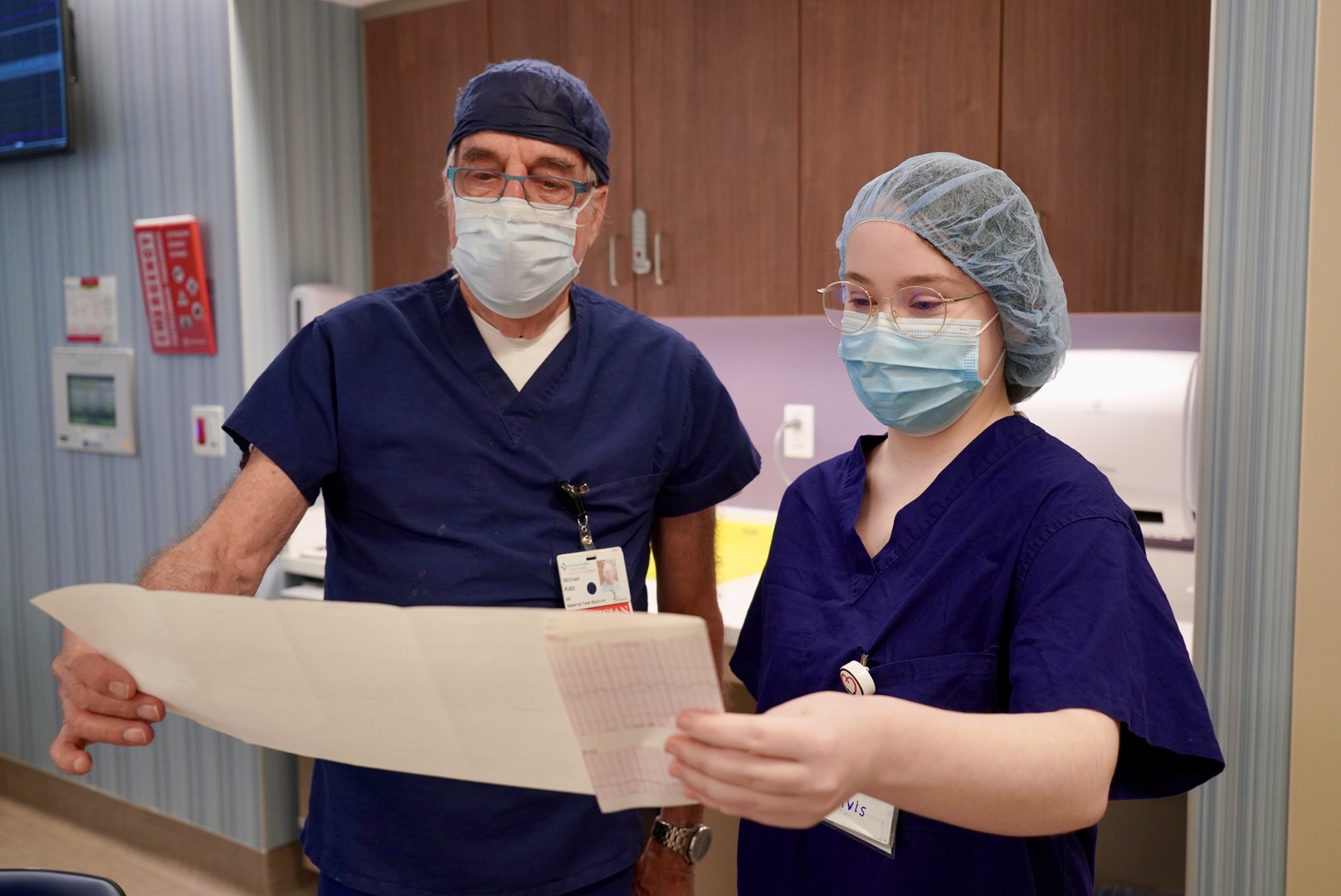 A doctor and student wearing scrubs review a patient's medical scan document.