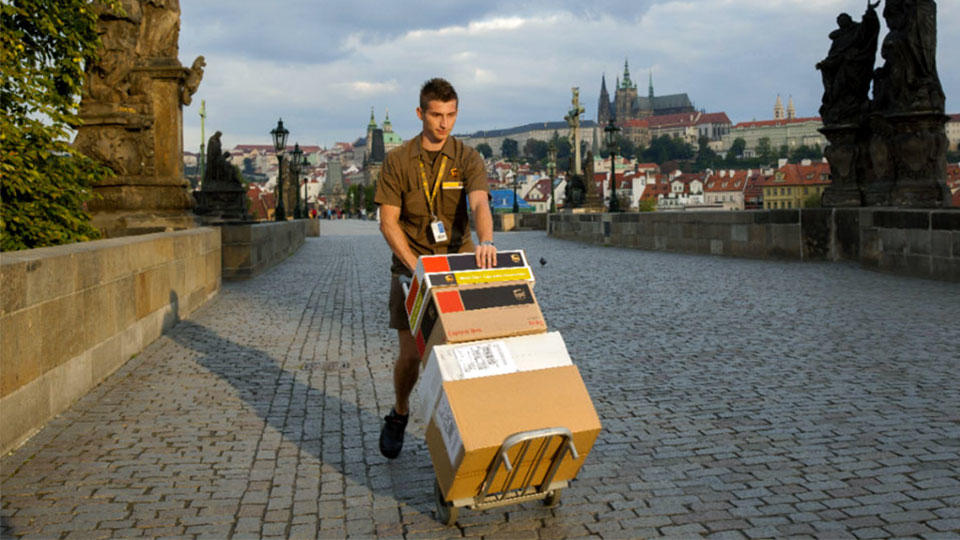 UPS driver transporting international deliveries using dolly