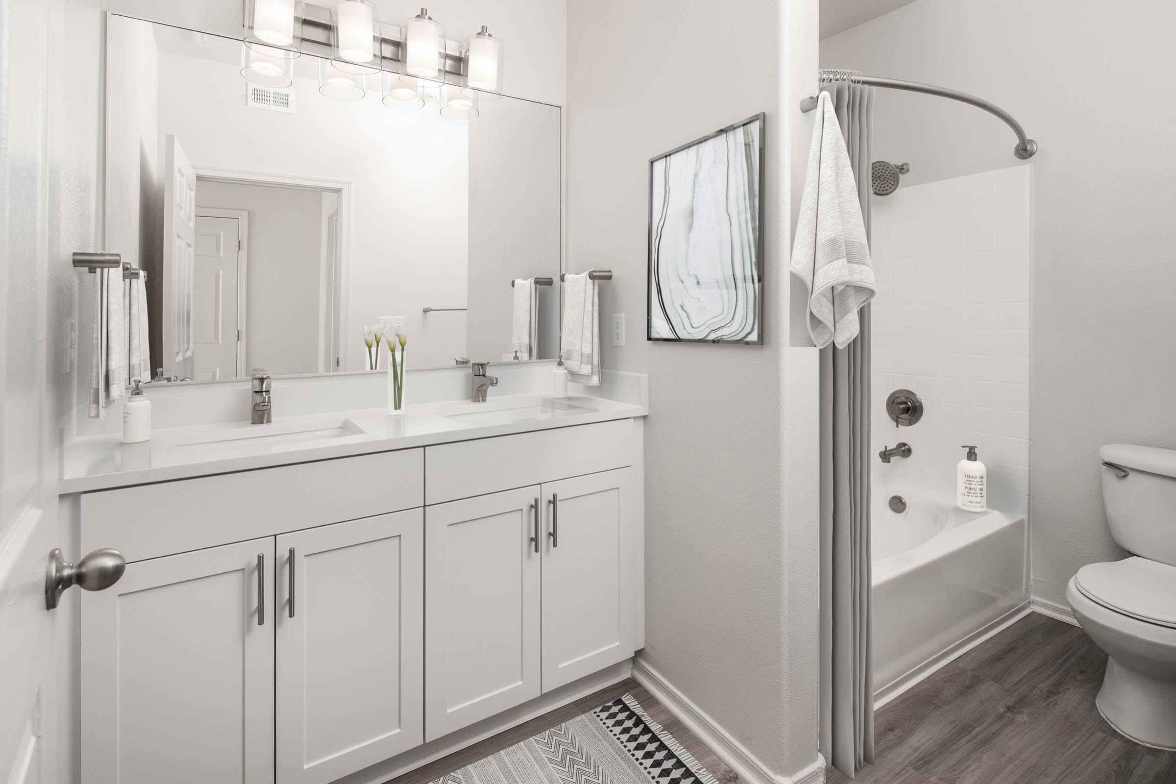 Luxurious main bathroom with dual sink vanity, white quartz countertops, brushed nickel fixtures, and curved shower rod