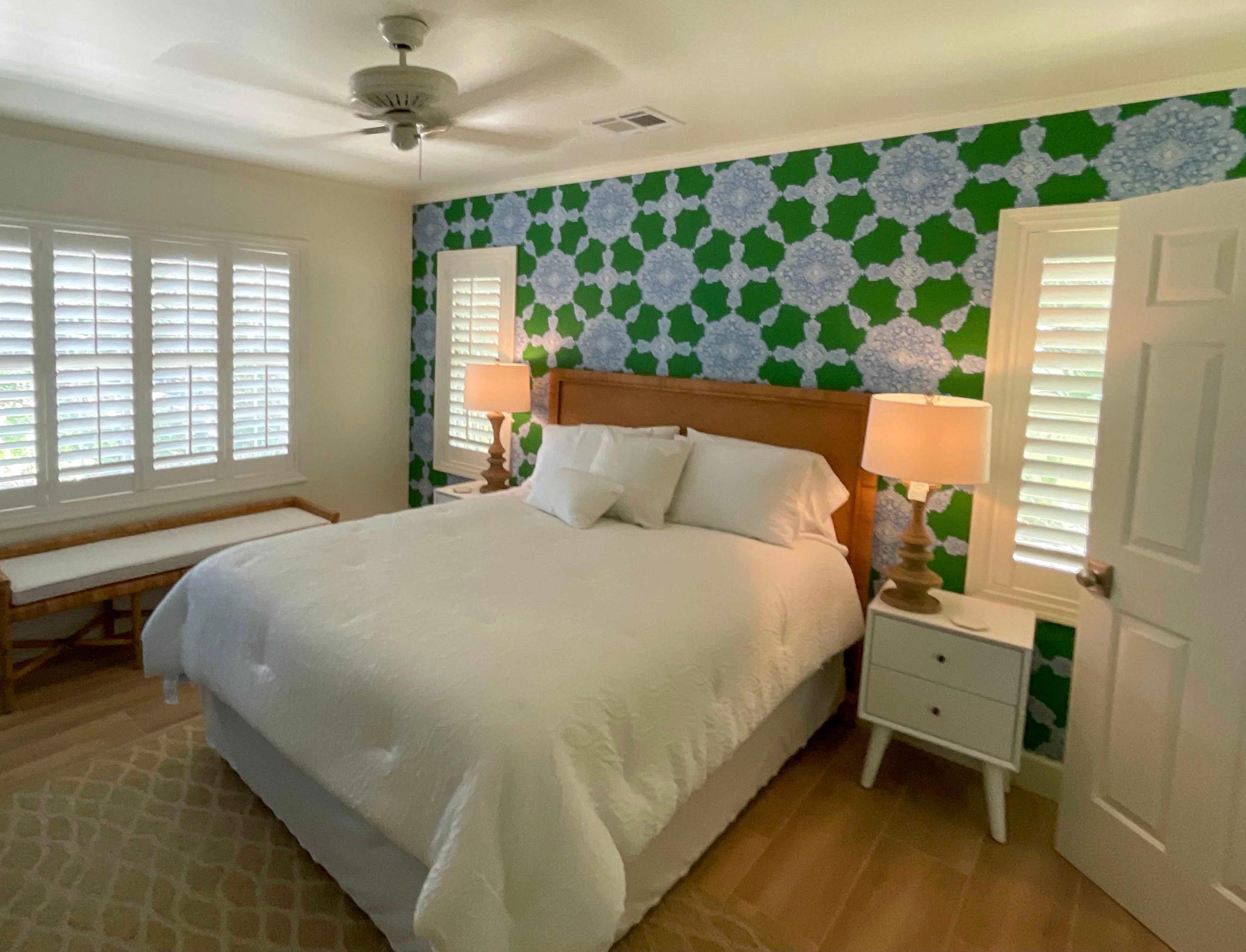 Choosing a simple white window treatment can balance out the bright colors in a space, like in this Vero Beach bedroom.