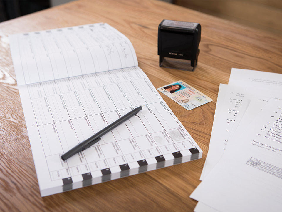 documents next to a notary stamp and notary logbook