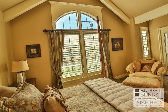 Custom Draperies and Plantation Shutters create quite the look in this bedroom in Mountain Home, ID. Leaving the arched window uncovered allows the room to bask in the natural light.  BudgetBlindsBoise  CustomDraperies  PlantationShutters  FreeConsultation  WindowWednesday  MountainHomeID