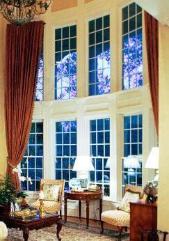 Large windows with side panel drapes add height and drama to room
