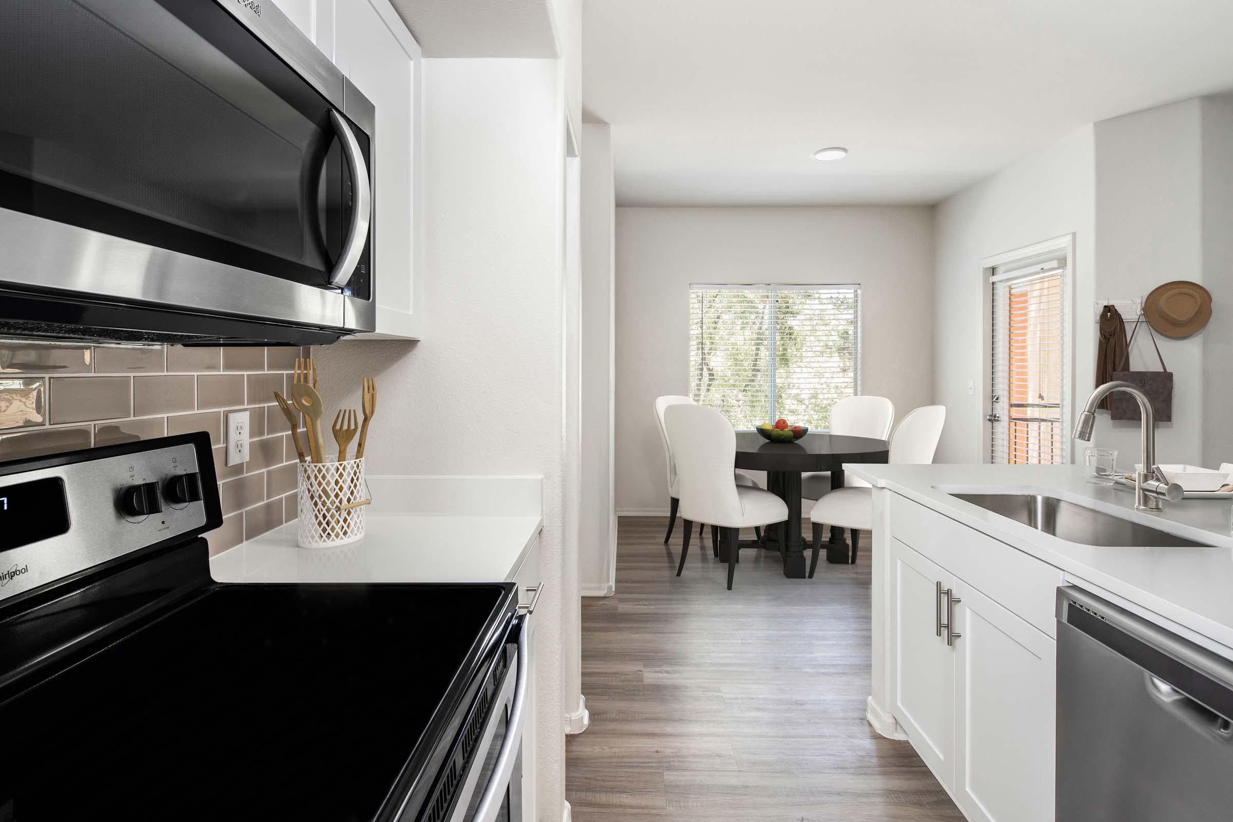 Open concept kitchen with stainless steel appliances, white quartz countertops, subway tile backsplash, and brushed nickel fixtures