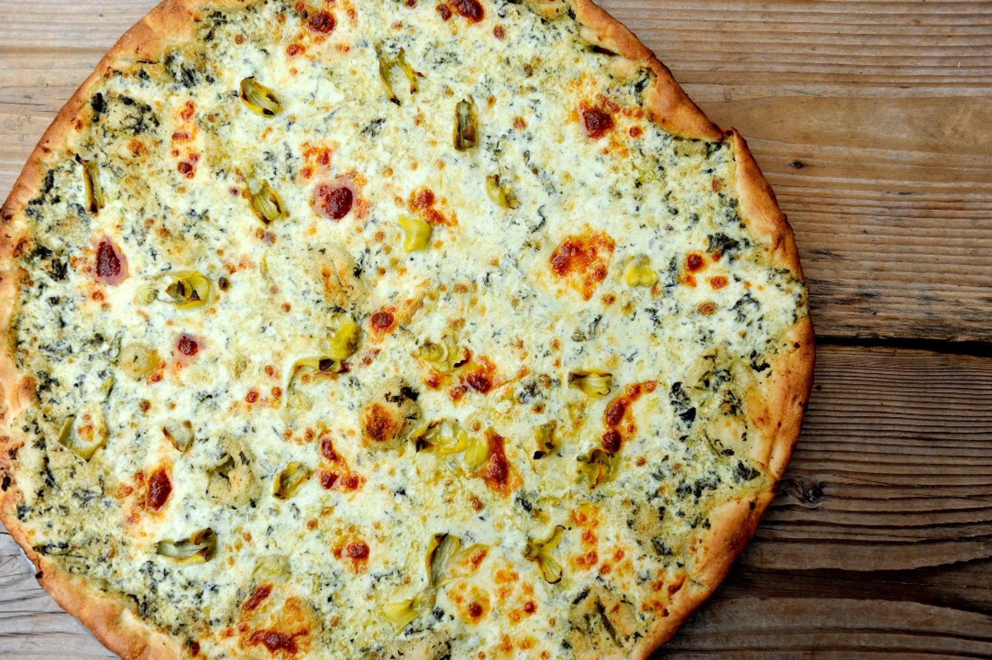Queens our delicious spinach & artichoke pizza with our housemade alfredo base, mozzarella, chedd...