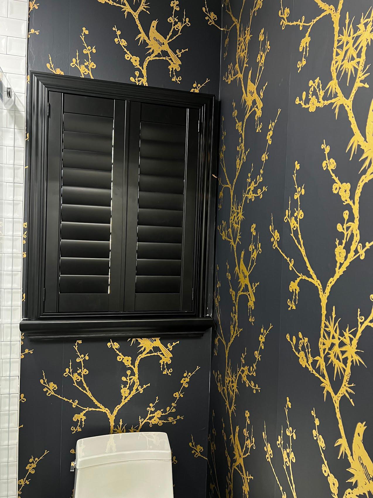 Here is an amazing reminder that you dont always have to go with the classic window treatments. These Midnight shutters in Colts Neck, NJ look perfect in this bathroom with the gold and black wallpaper.