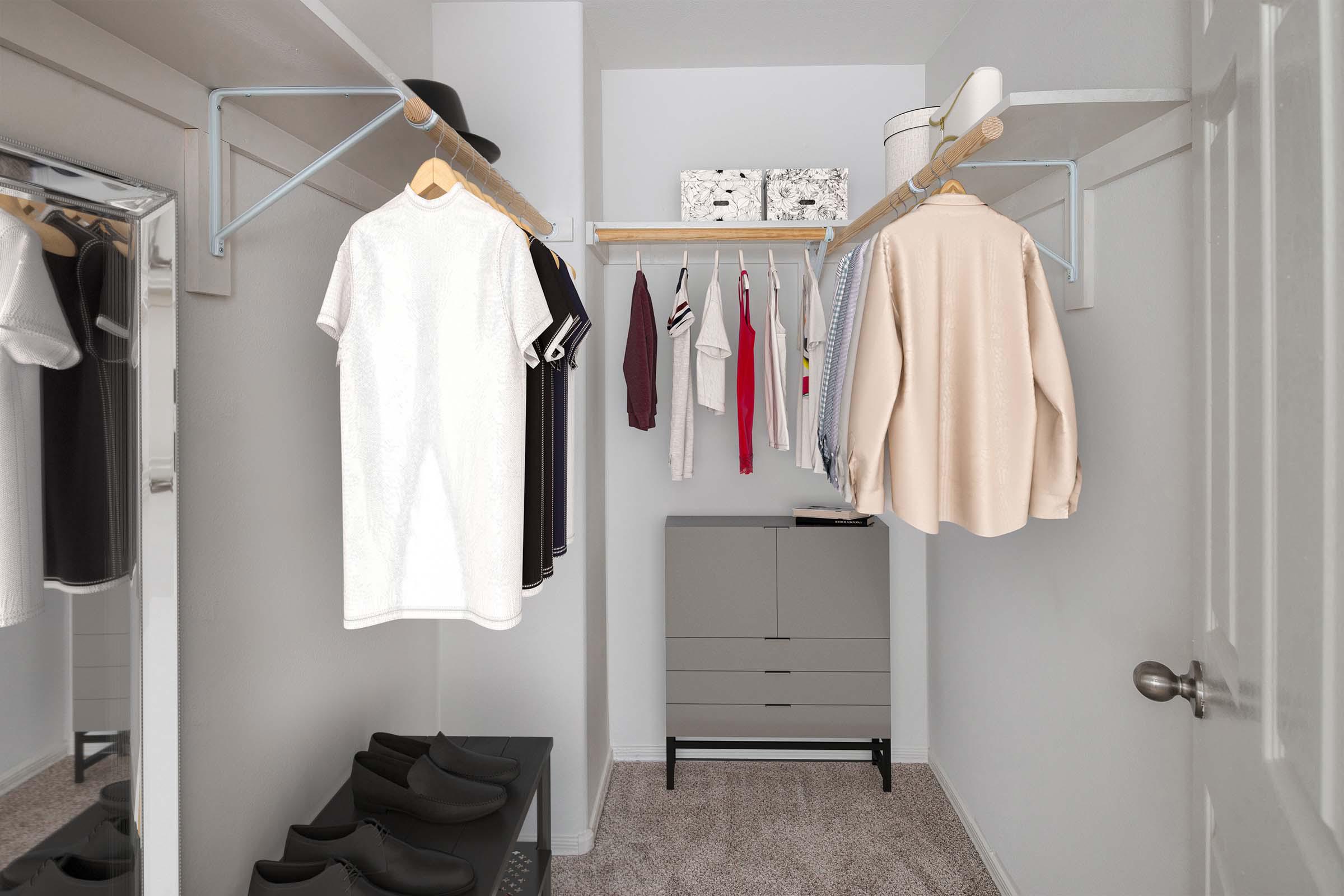 Walk-in closet with wood shelves, rods, and room for dressers