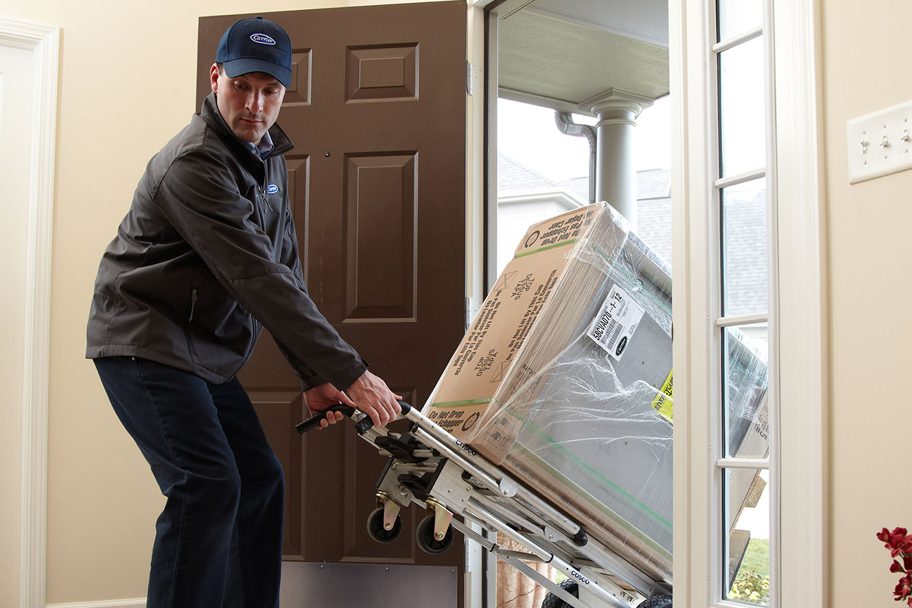 A dealer carrying a furnace on a dolly for an HVAC installation