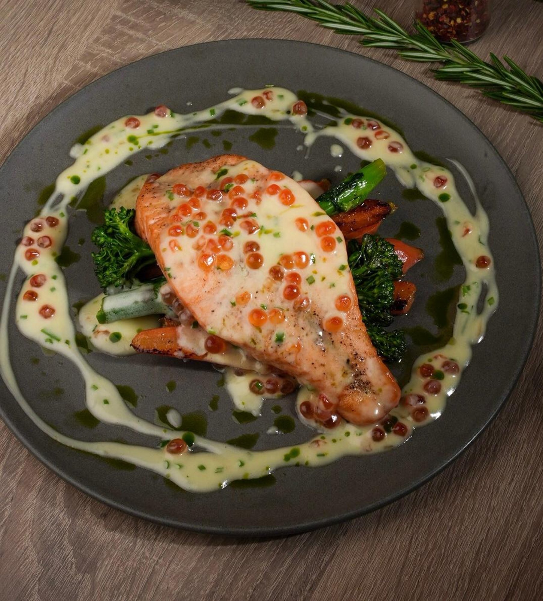 Salmon steak with creamy sauce, red caviar, broccolini and carrots