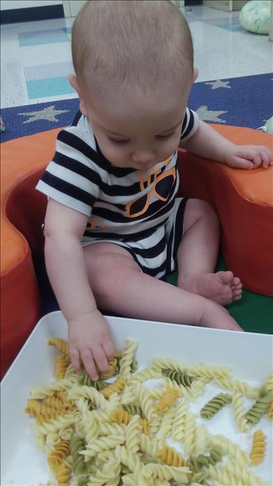 Our infants work hard daily by using their senses. Our curriculum allows our babies to explore different foods. Here is Joseph exploring cooked pasta.