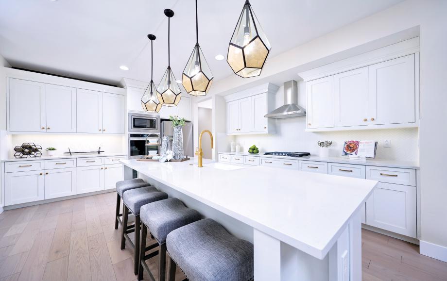 Crisp white kitchen with gold accents and gorgeous glass pendant lights