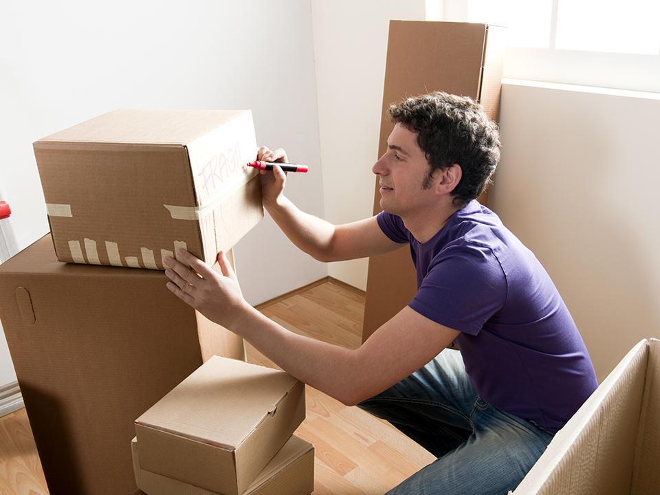 a man labeling a packed moving box