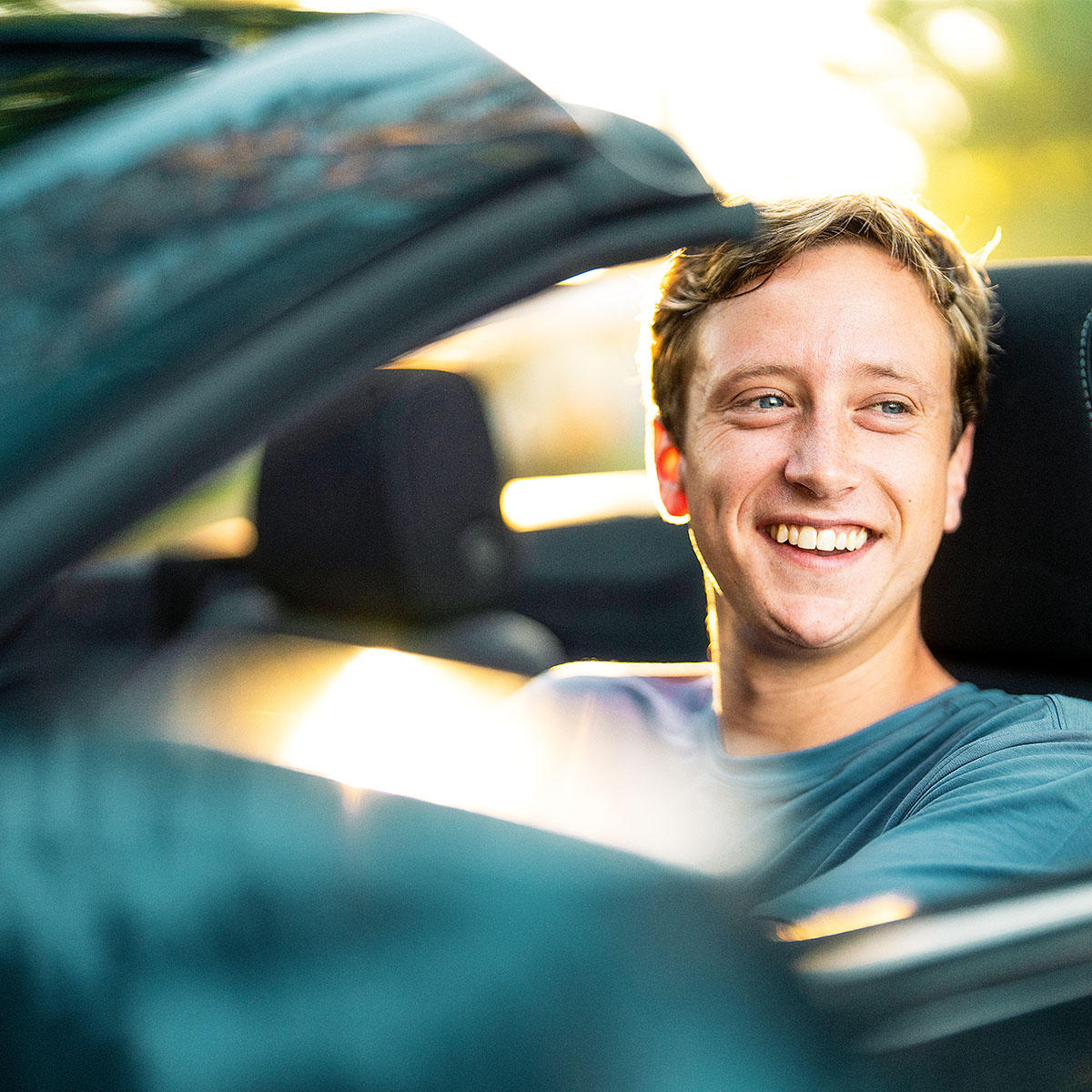 Enterprise customer smiling while driving a convertible rental car