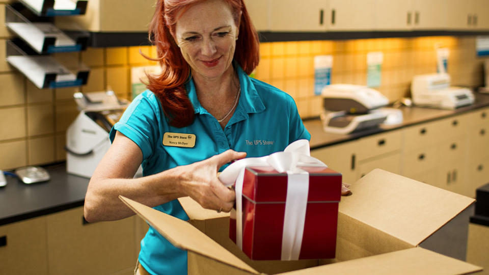 Employee shipping red gift with white bow