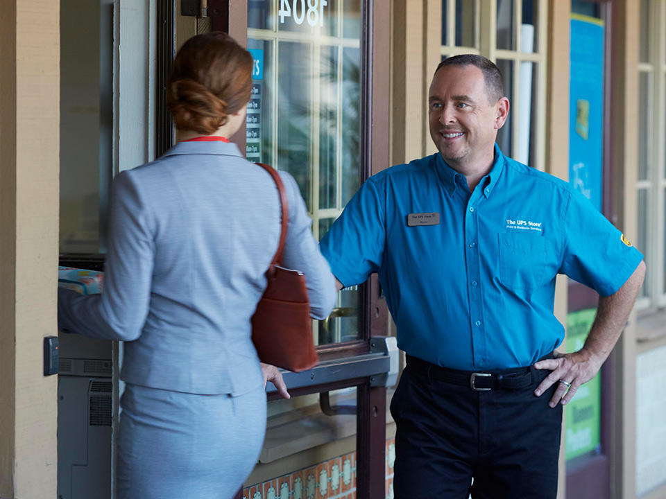 ups store male franchisee opening door to female customer in business suit