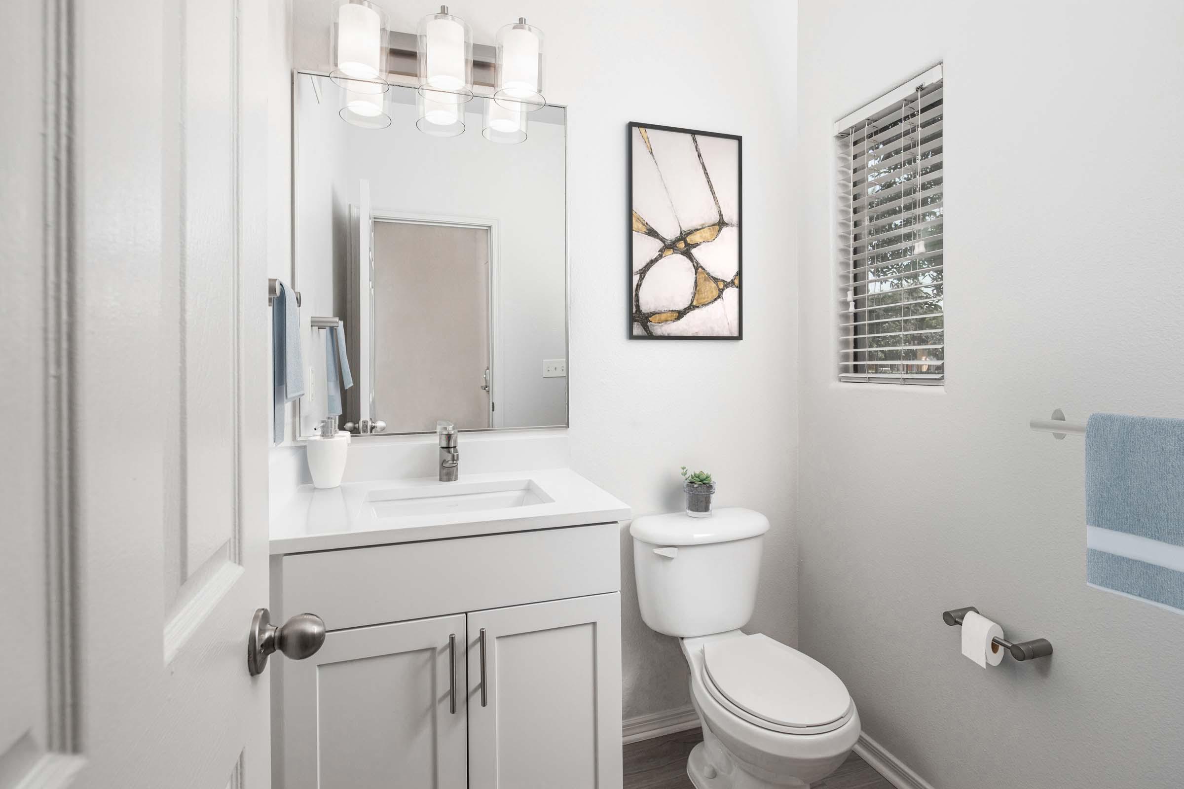 Powder bathroom with white shaker cabinets and white quartz countertops