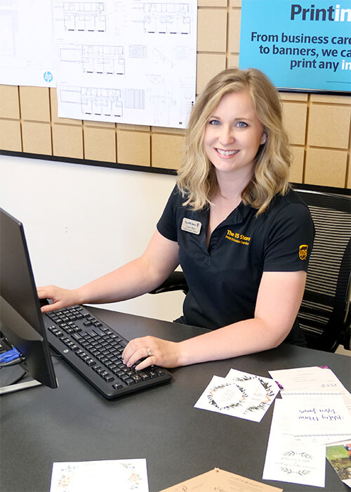 Associate in front of printed wedding materials at The UPS Store in Fargo, ND