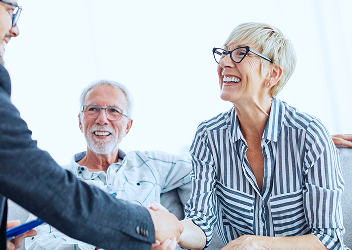 An elderly couple shaking hands with their advisor.