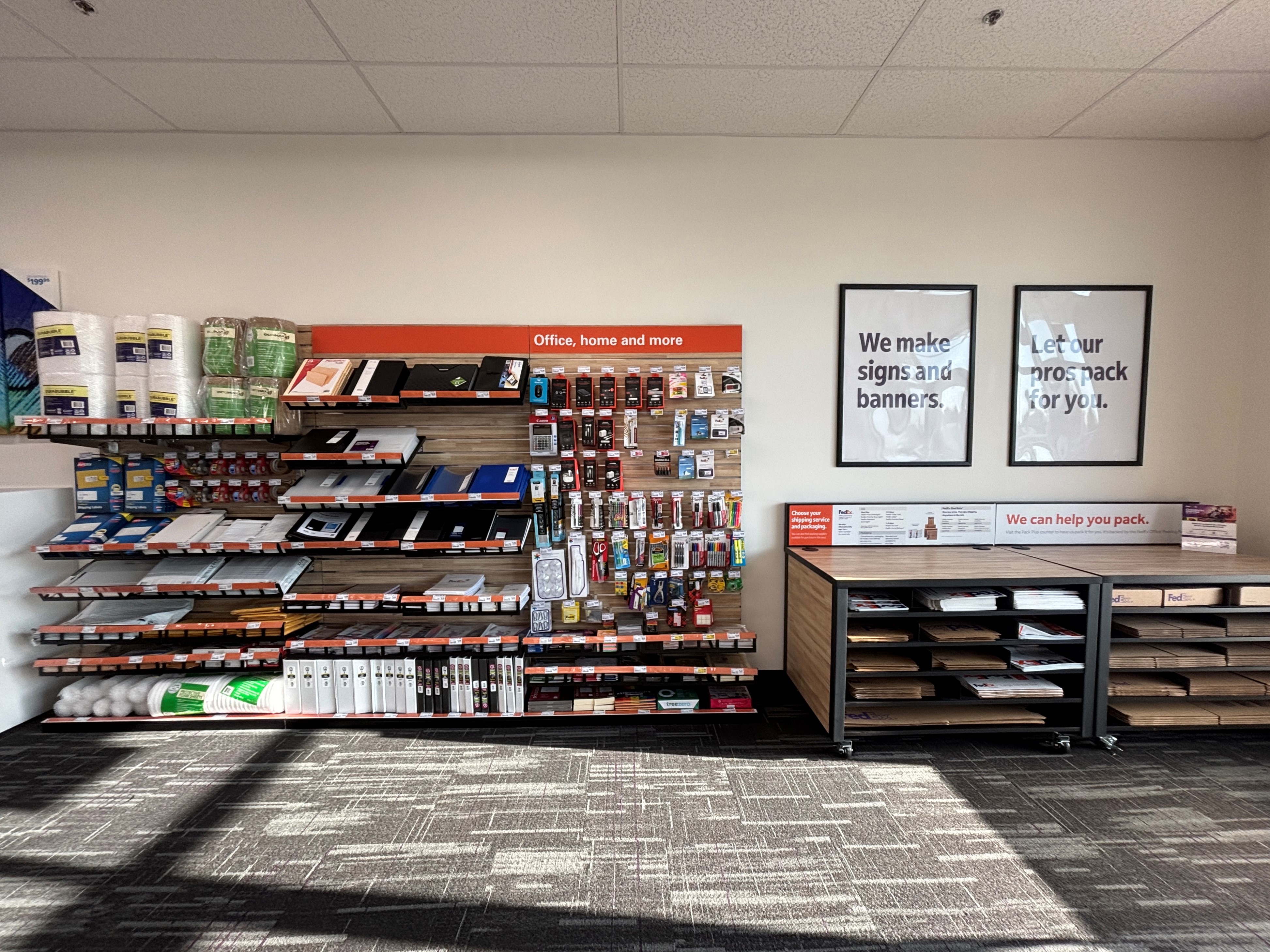 The retail wall featuring office supplies and a self-service packing station with FedEx mailers at the Temple location.