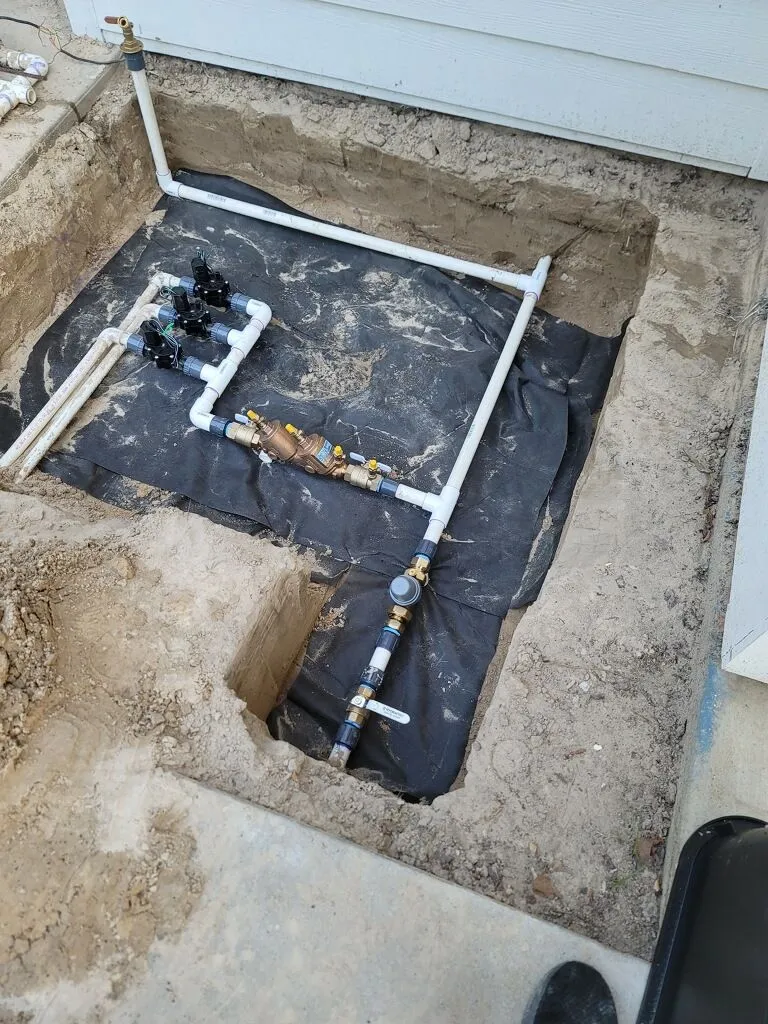 Underground residential water service installation features pressure regulator, shutoff valves, and PVC piping within prepared excavation, ensuring reliable water distribution, efficient plumbing performance, and long-term infrastructure durability for homeowners.