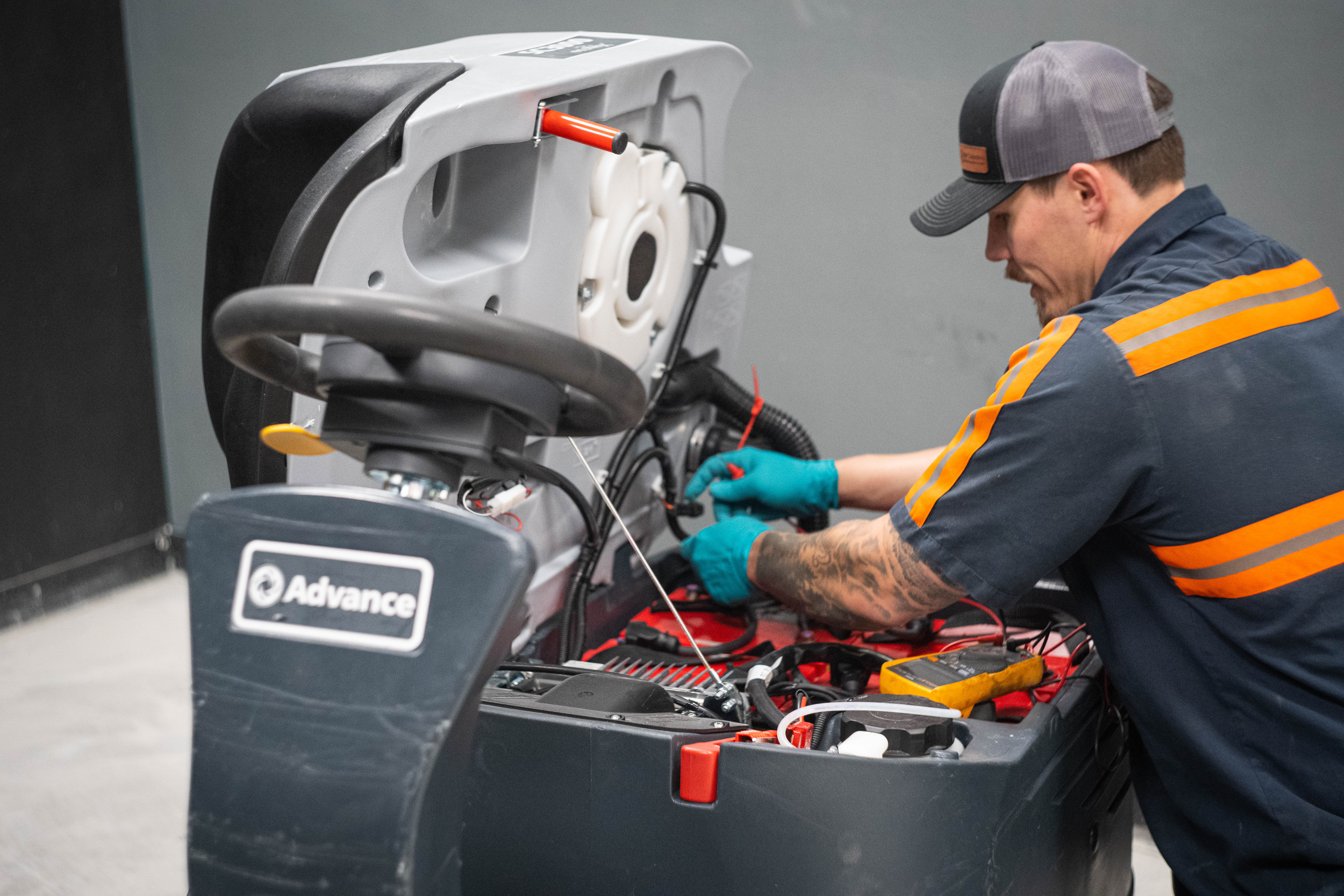 An expert WaySolutions technician uses a digital multimeter to perform precision electrical diagnostics on an Advance ride-on commercial floor scrubber. By testing the internal wiring and battery system directly, we accurately identify electrical faults and provide reliable, long-lasting repairs for high-capacity industrial and retail cleaning fleets across the Layton area.