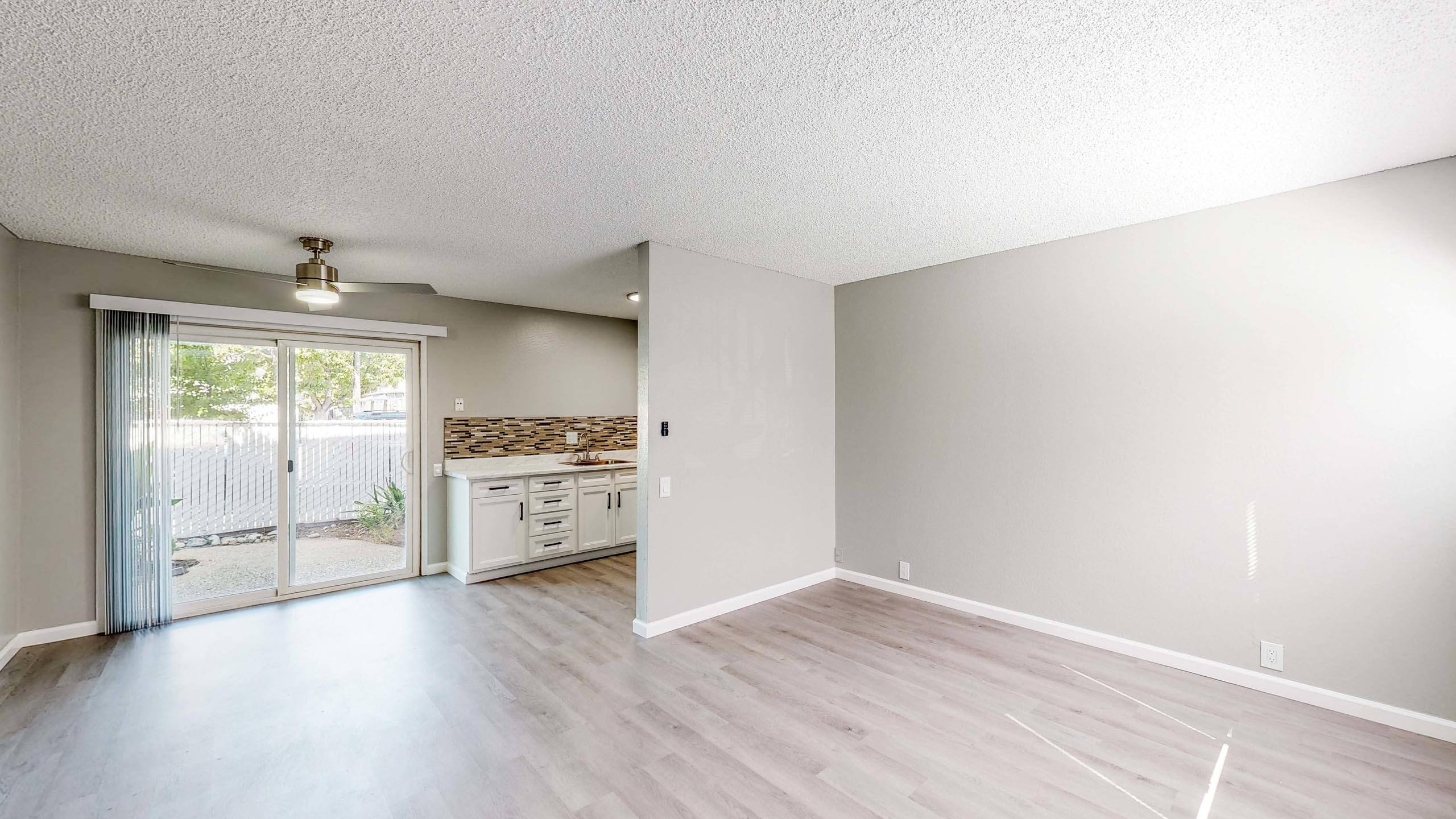 A room with a sliding glass door leading to a backyard at University Square Apartments, Davis, California