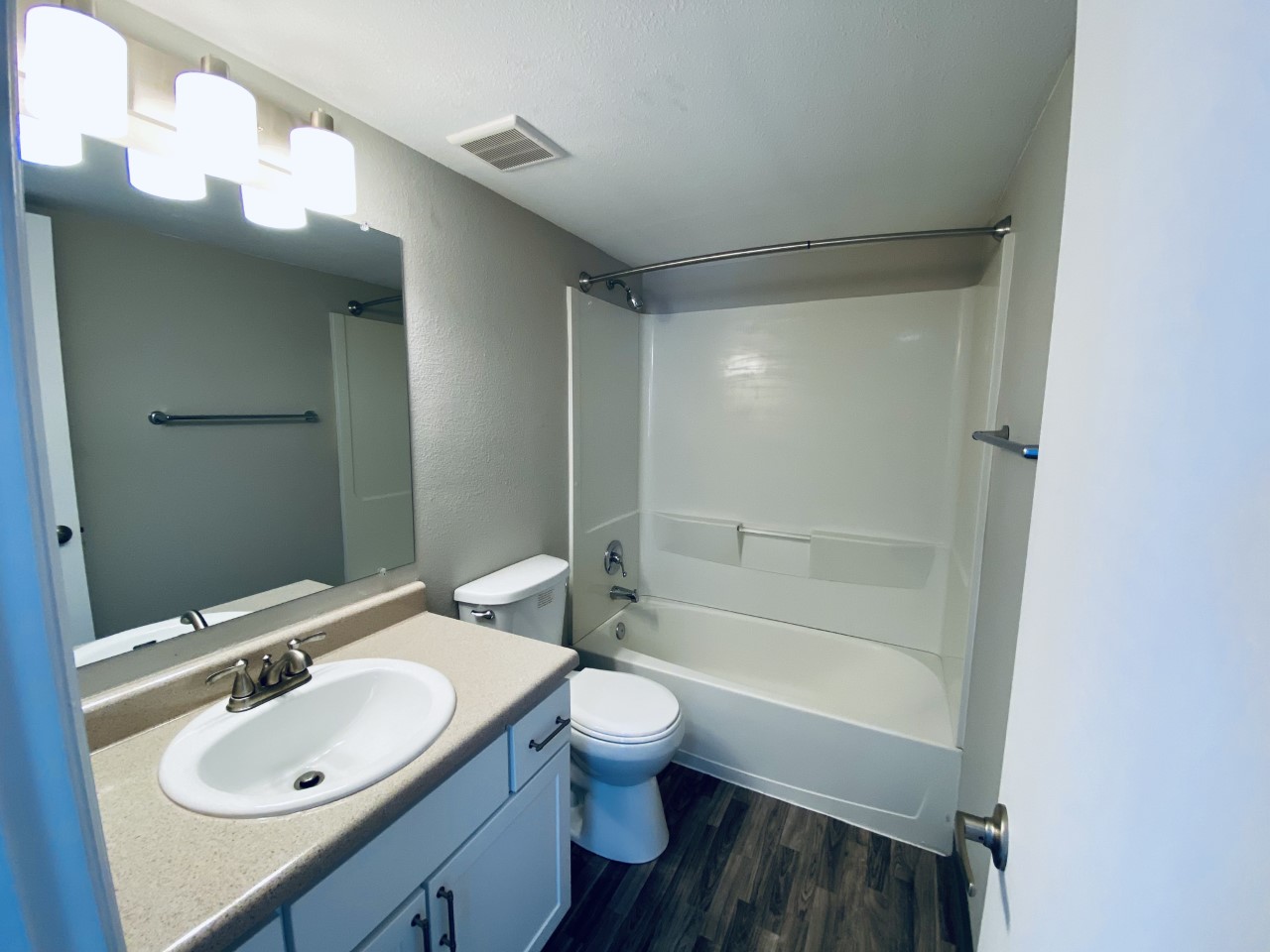 Vinyl-floored bathroom with counter and shower bathtub combination.
