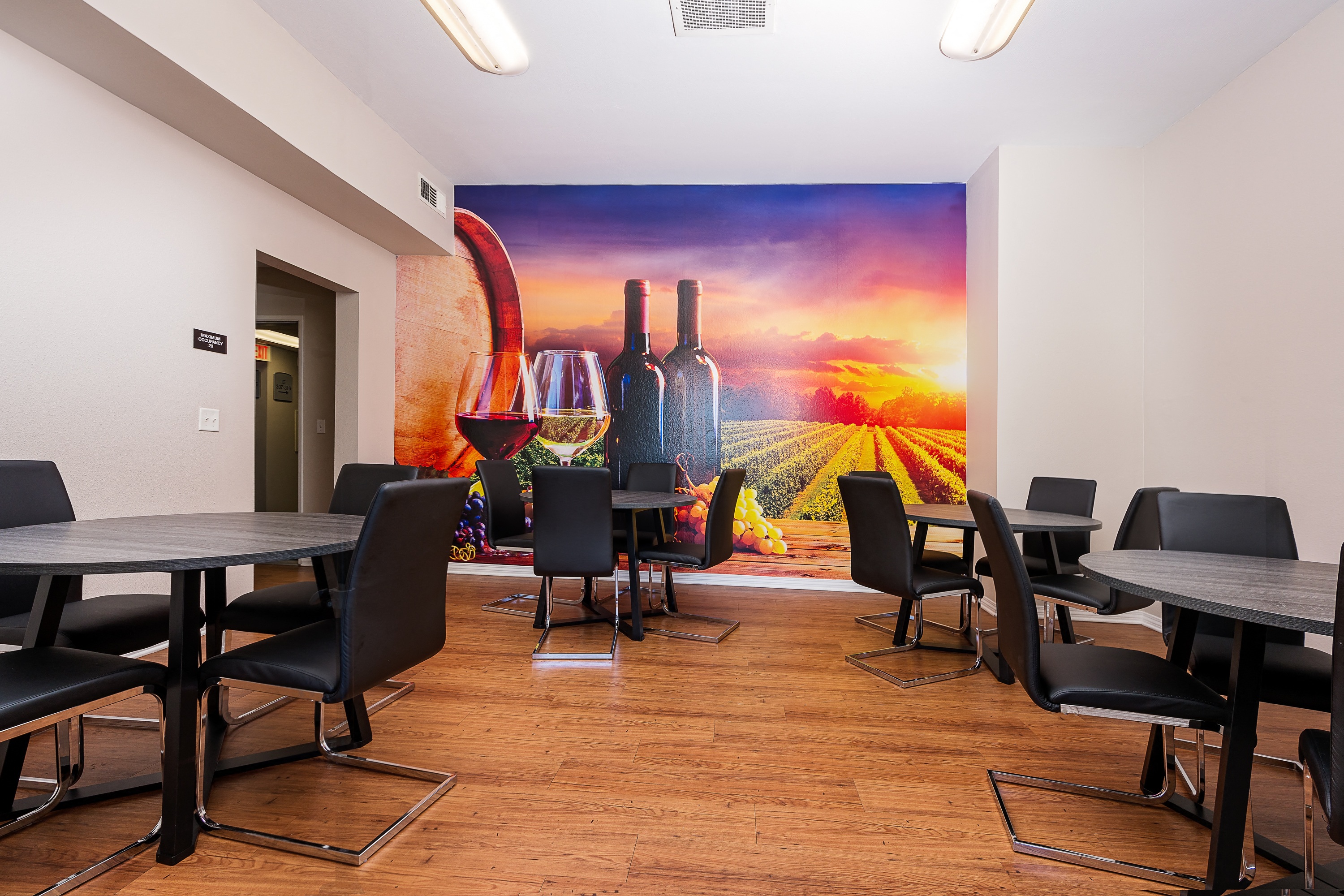 a room with tables and chairs and a mural of wine bottles and glasses on the wall 