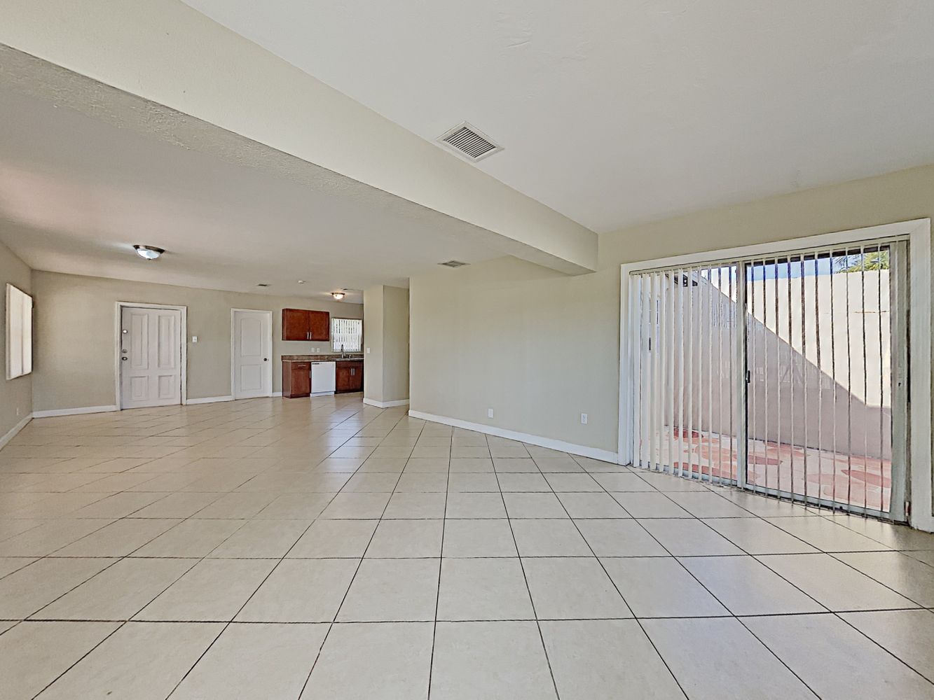 Spacious living space with neutral tile and easy access to the backyard at Invitation Homes South Florida.