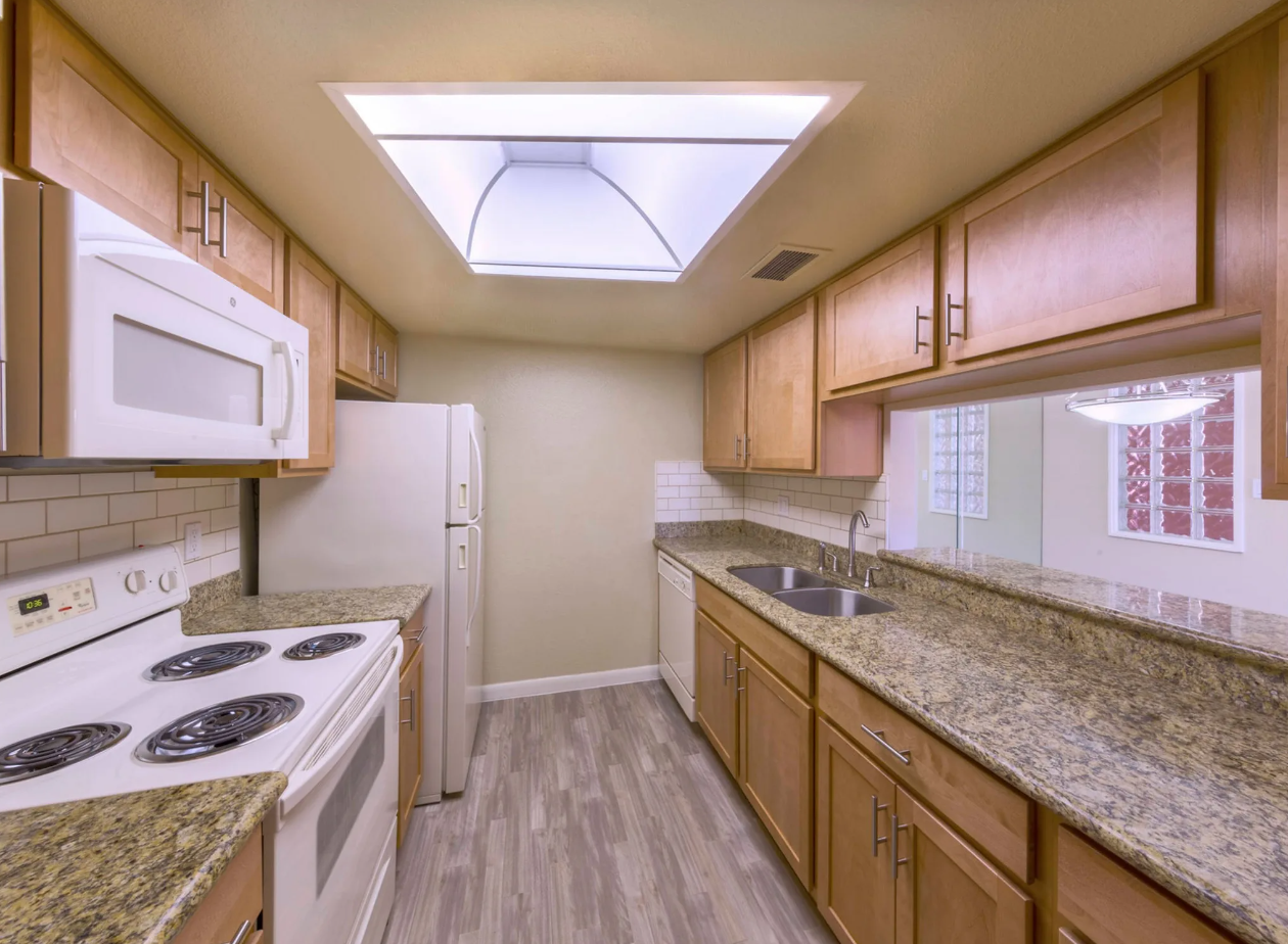 Kitchen with Dark Wooden Cabinets, White Appliances, and Overhead Lighting