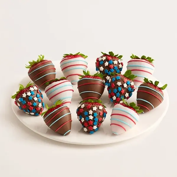 A white platter displays a collection of twelve chocolate-covered strawberries, adorned with red, wh 