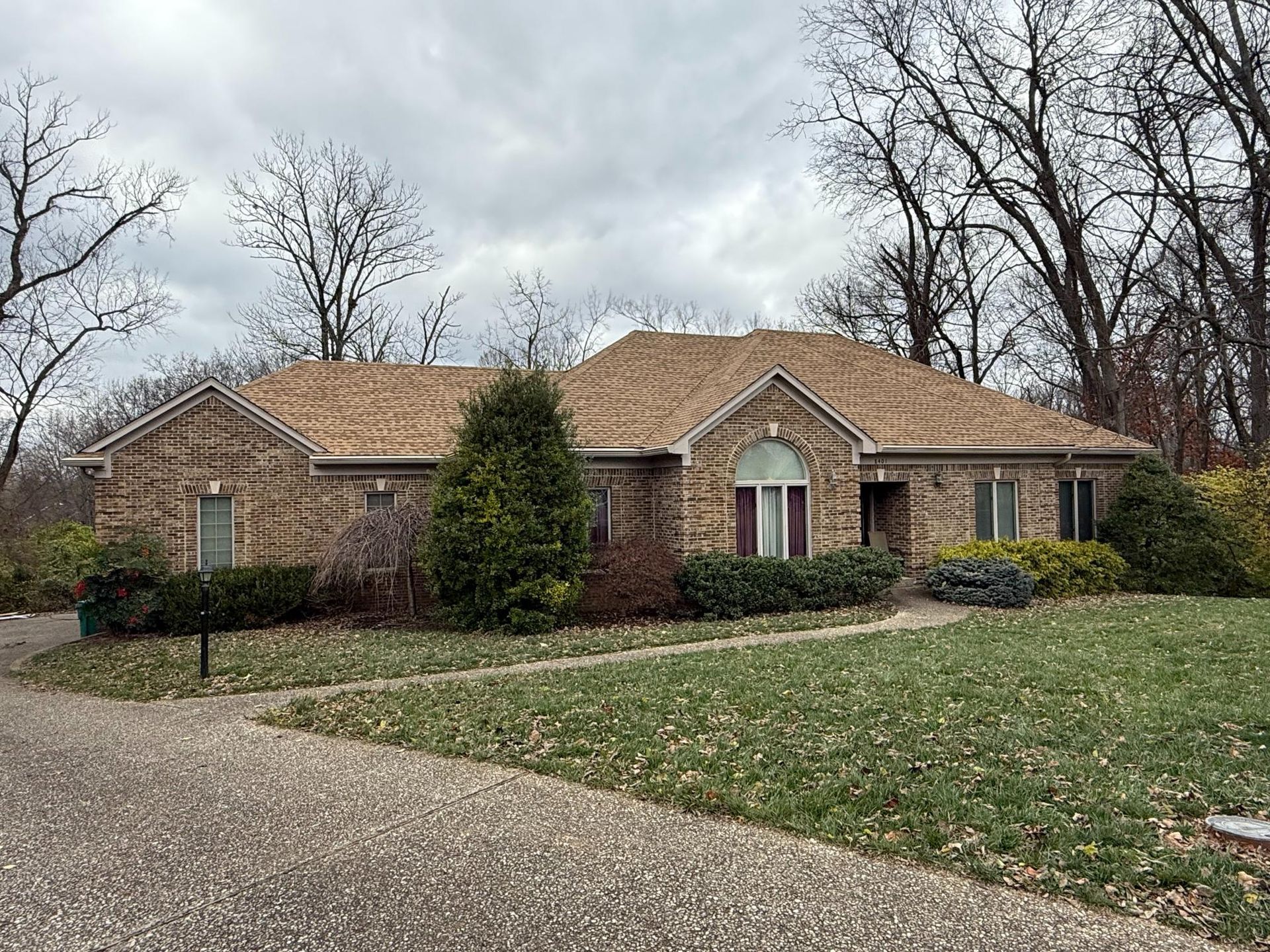 Front view of a large brick home featuring a newly installed tan asphalt shingle roof with clean rid 