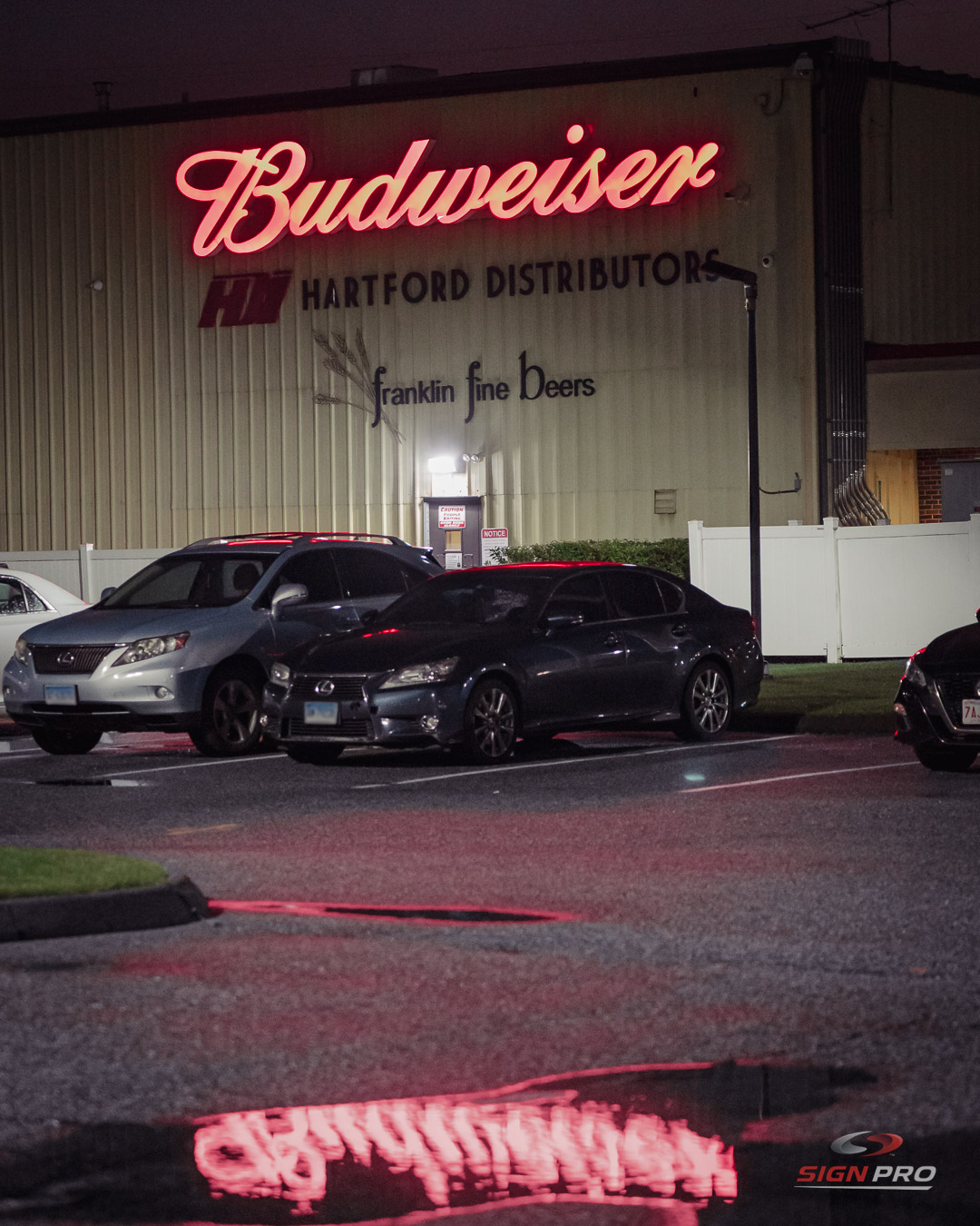 Illuminated exterior signage manufactured and installed by Sign Pro for Hartford Distributors, creating a striking nighttime brand presence.