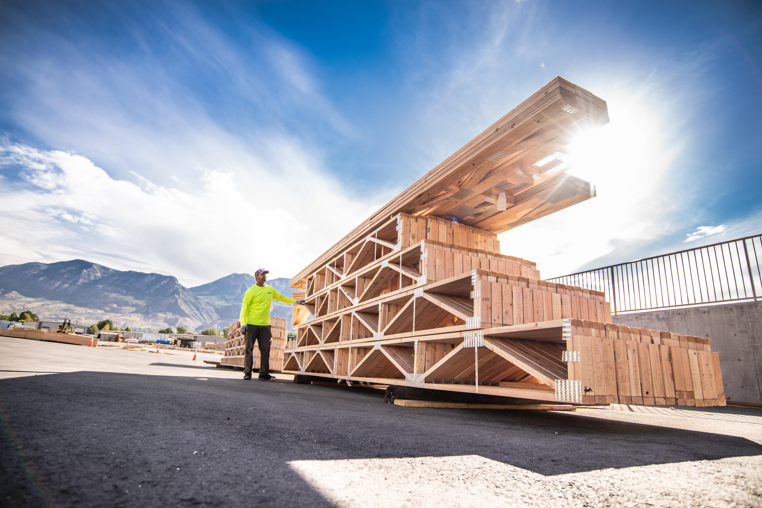 Builders FirstSource employee at truss plant inspecting floor and roof trusses.