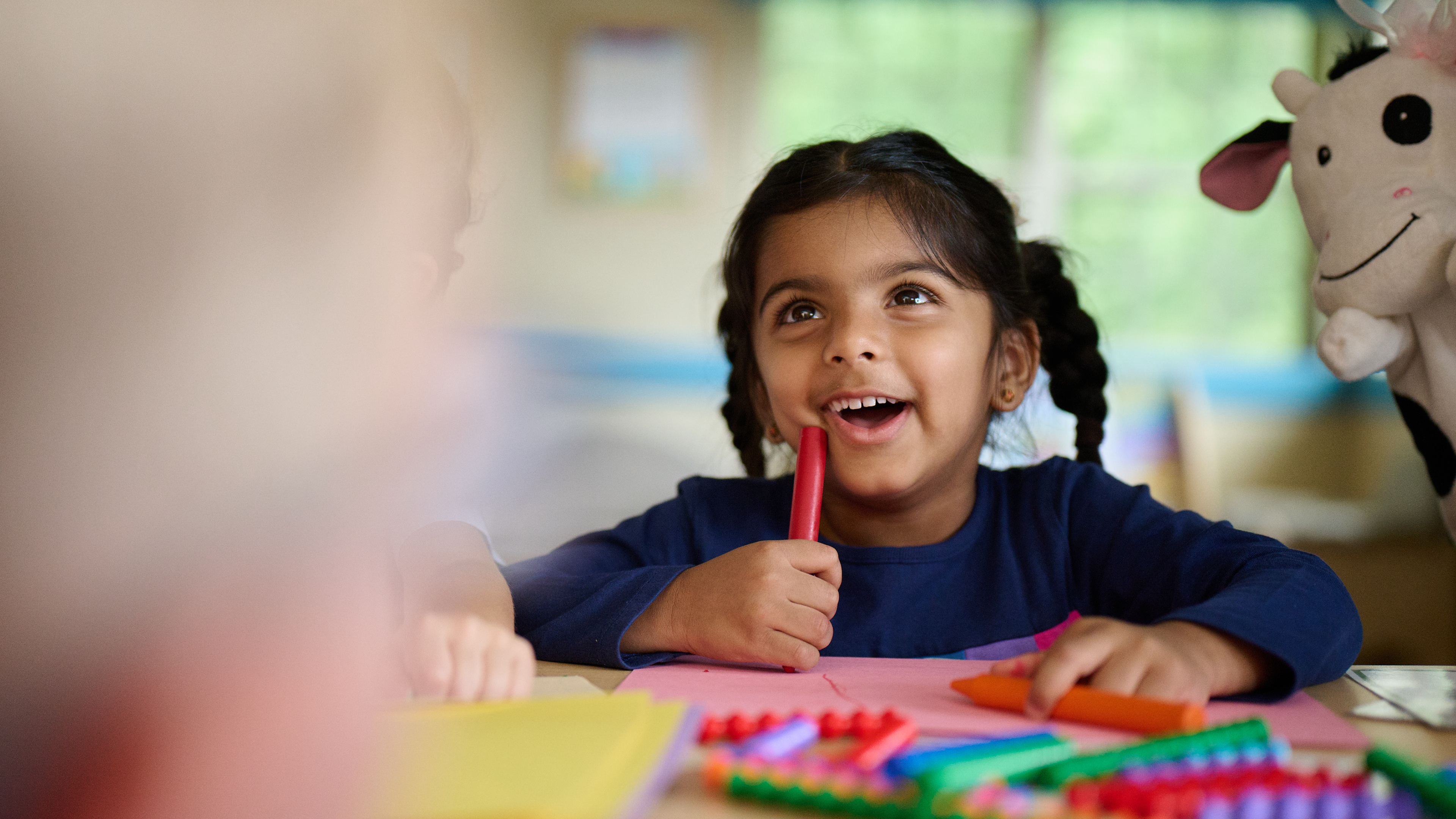 Primrose Schools preschool girl smiling during creative art activity with crayons in early learning classroom