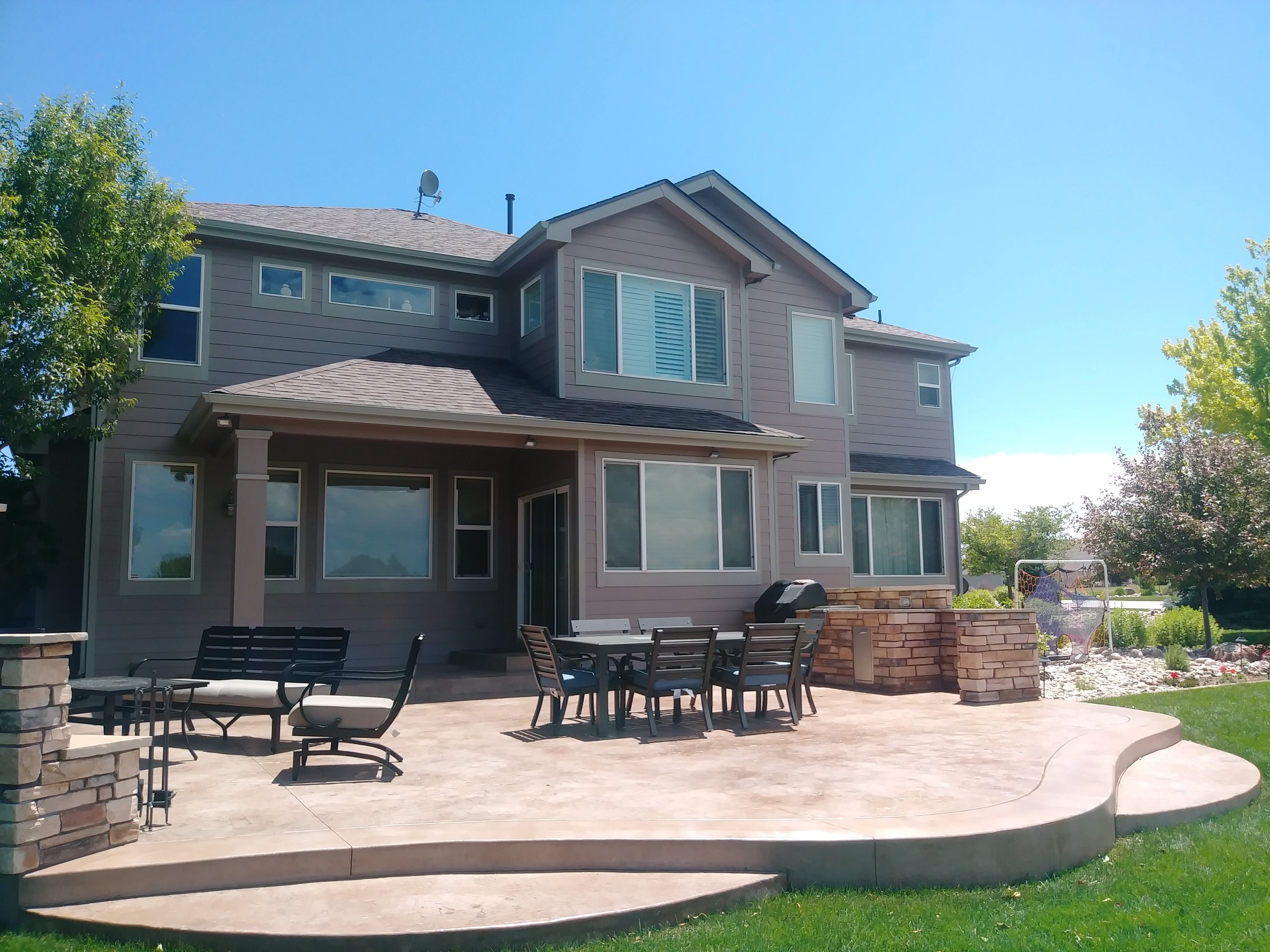 Spacious residential concrete patio with rounded edges and a warm decorative finish, creating an inviting outdoor entertaining and dining area.