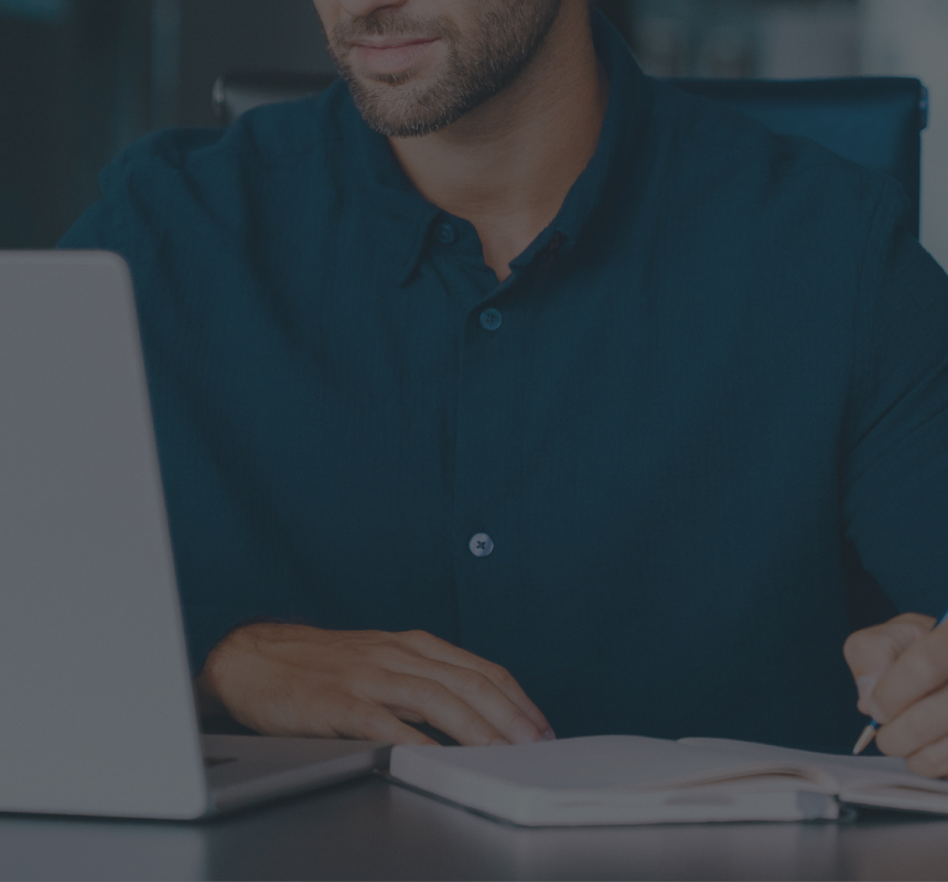 A professional working at desk with laptop and documents in modern office.