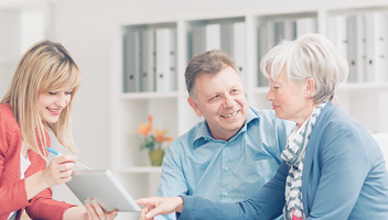An elderly couple reviewing documents with their advisor.