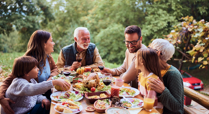 A multigenerational family gathered around an outdoor dinner table.