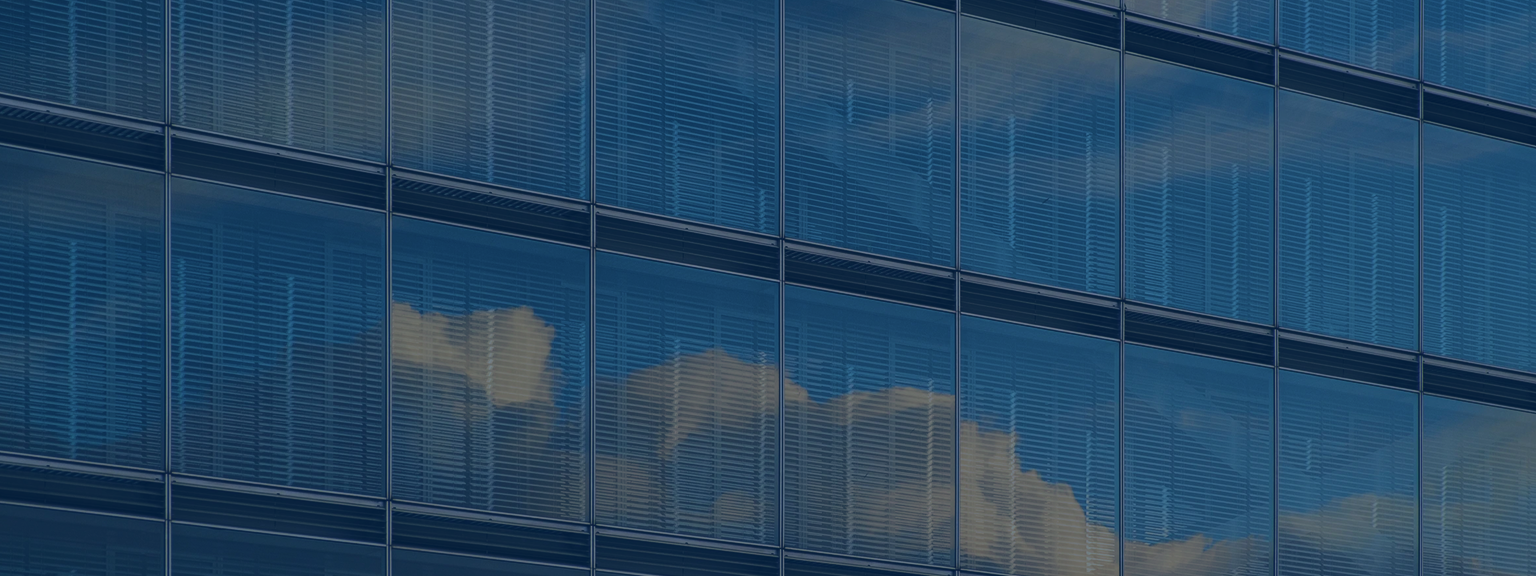 Close-up of a modern glass office building with clouds reflected in the windows.