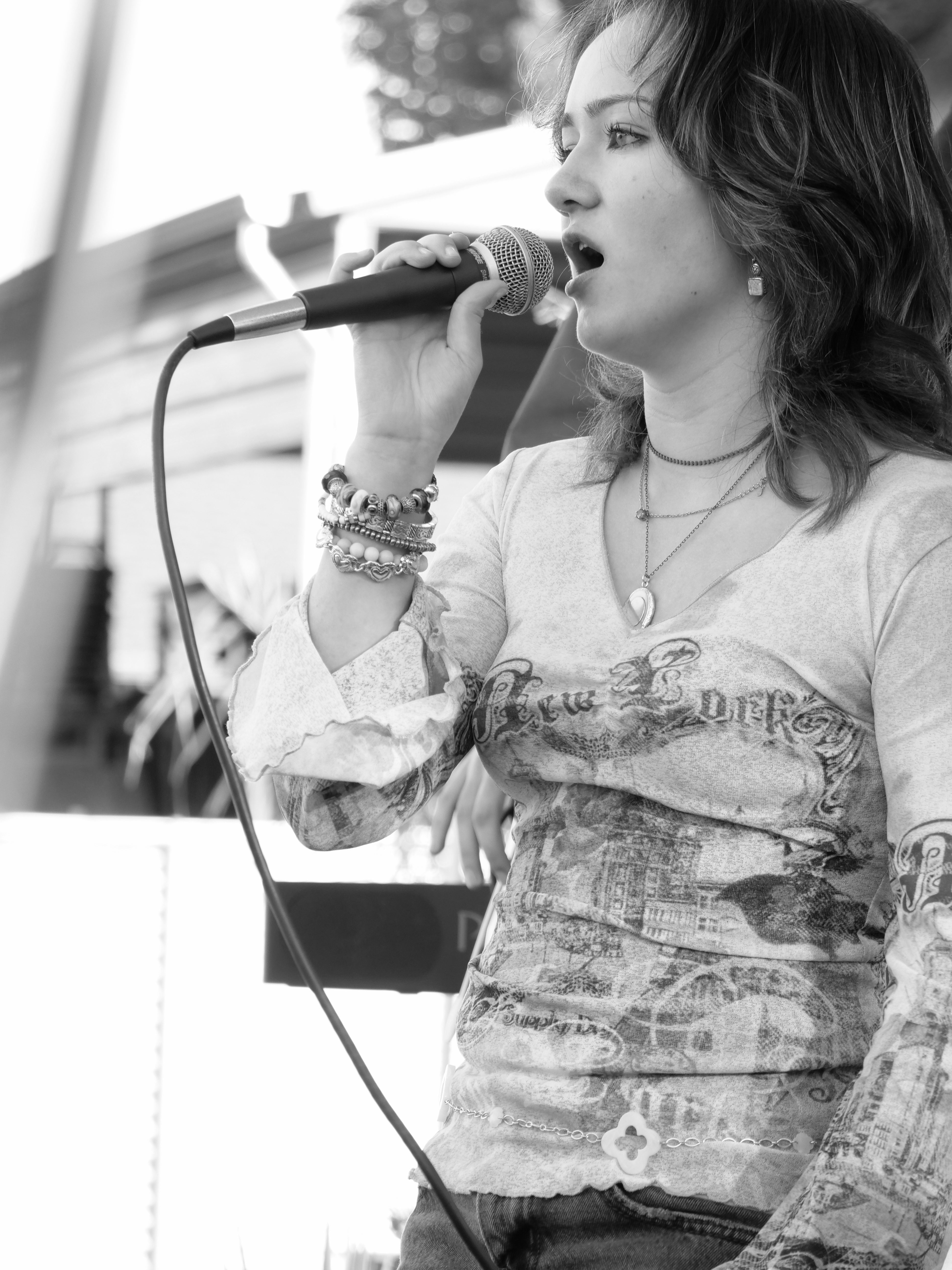 Black-and-white portrait of a student vocalist performing live during a music showcase event.