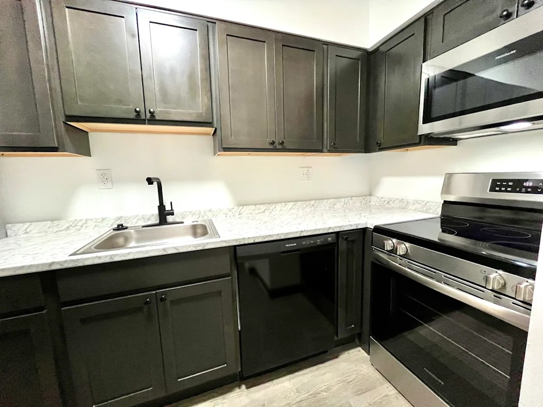 Updated kitchen with dark cabinets and stainless steel appliances,