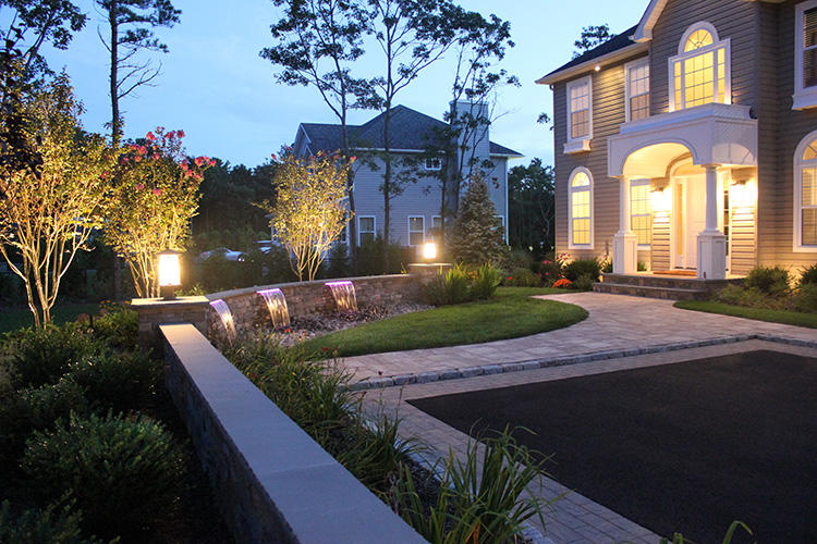 Pavers, paver ledge wall with fountain spillover accented by lighting at night