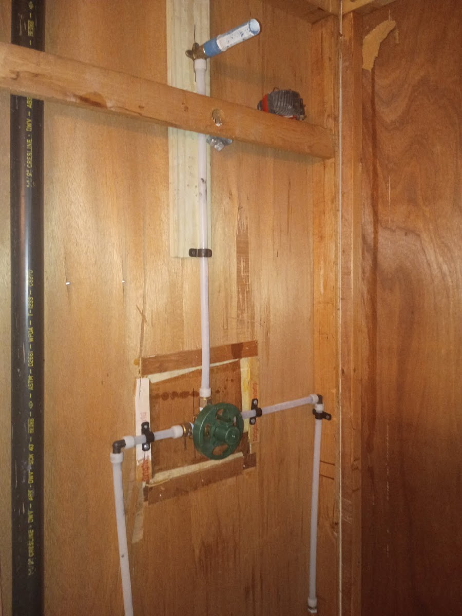 Shower valve and piping installation with wall access opened for plumbing repair or fixture replacement.