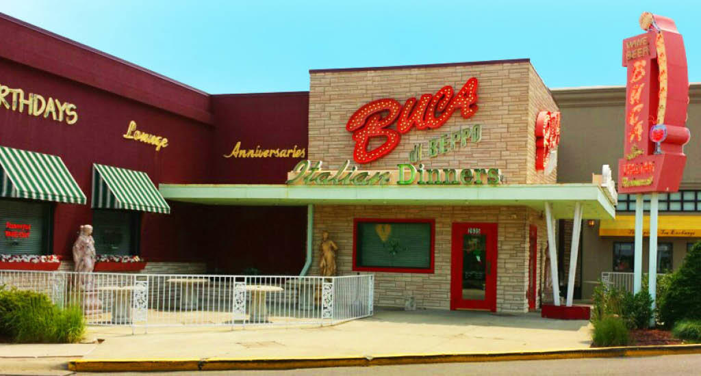 Buca di Beppo Cincinnati with signs all over the building, statues, and red Buca road sign.